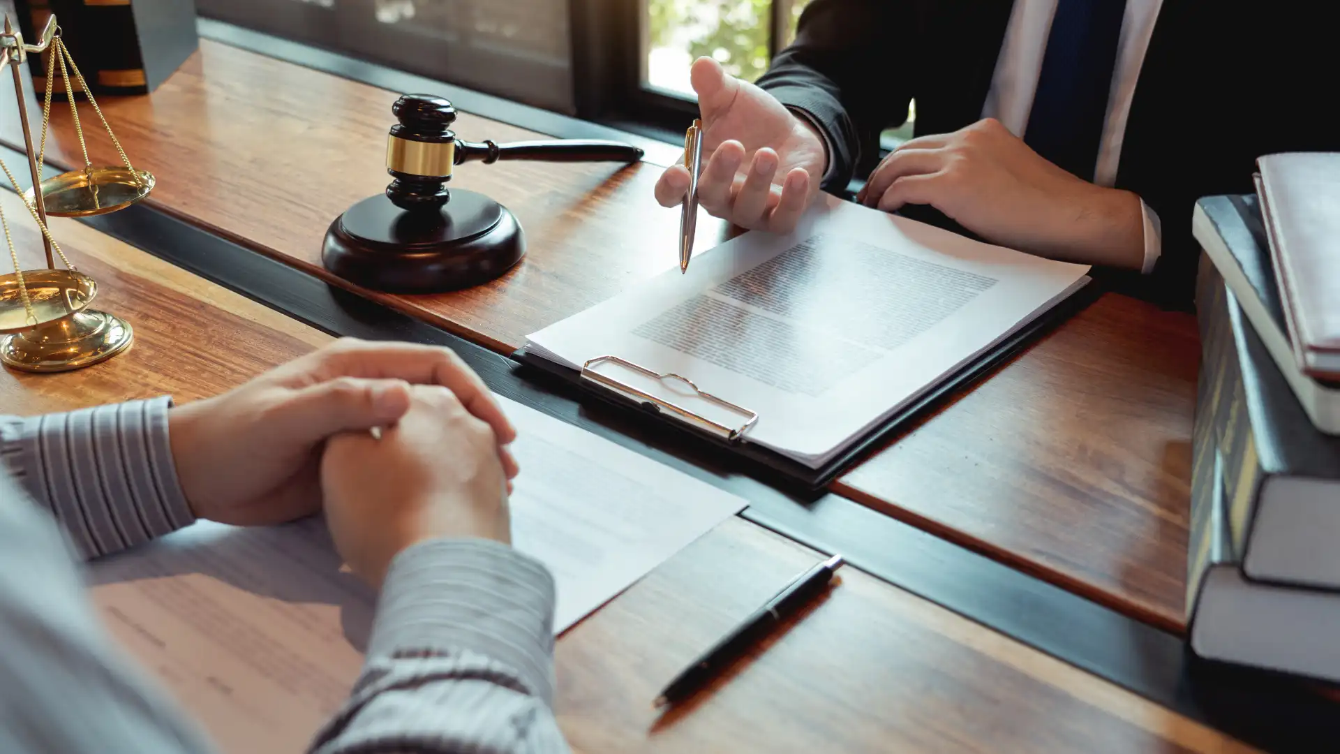 Client and lawyer discussing legal document with gavel on desk.