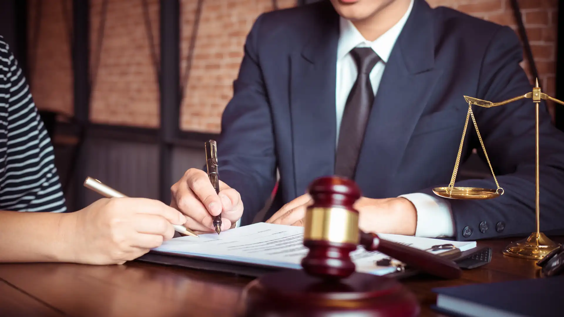 Lawyer filling out legal document with gavel in foreground.