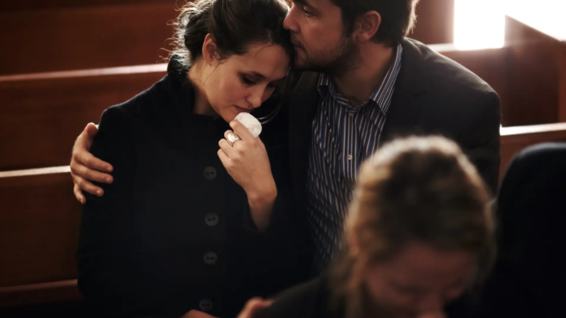 "Couple comforting each other, with the woman holding a tissue and the man embracing her