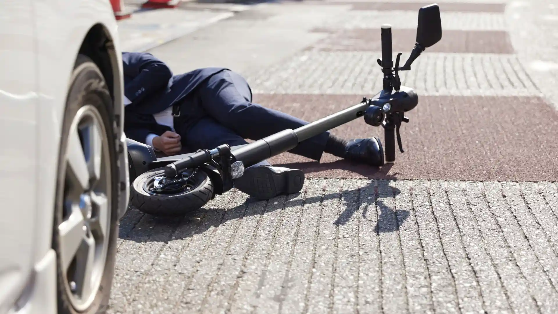 Person lying on ground after electric scooter accident.