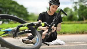 Injured cyclist sitting on ground after bike accident.