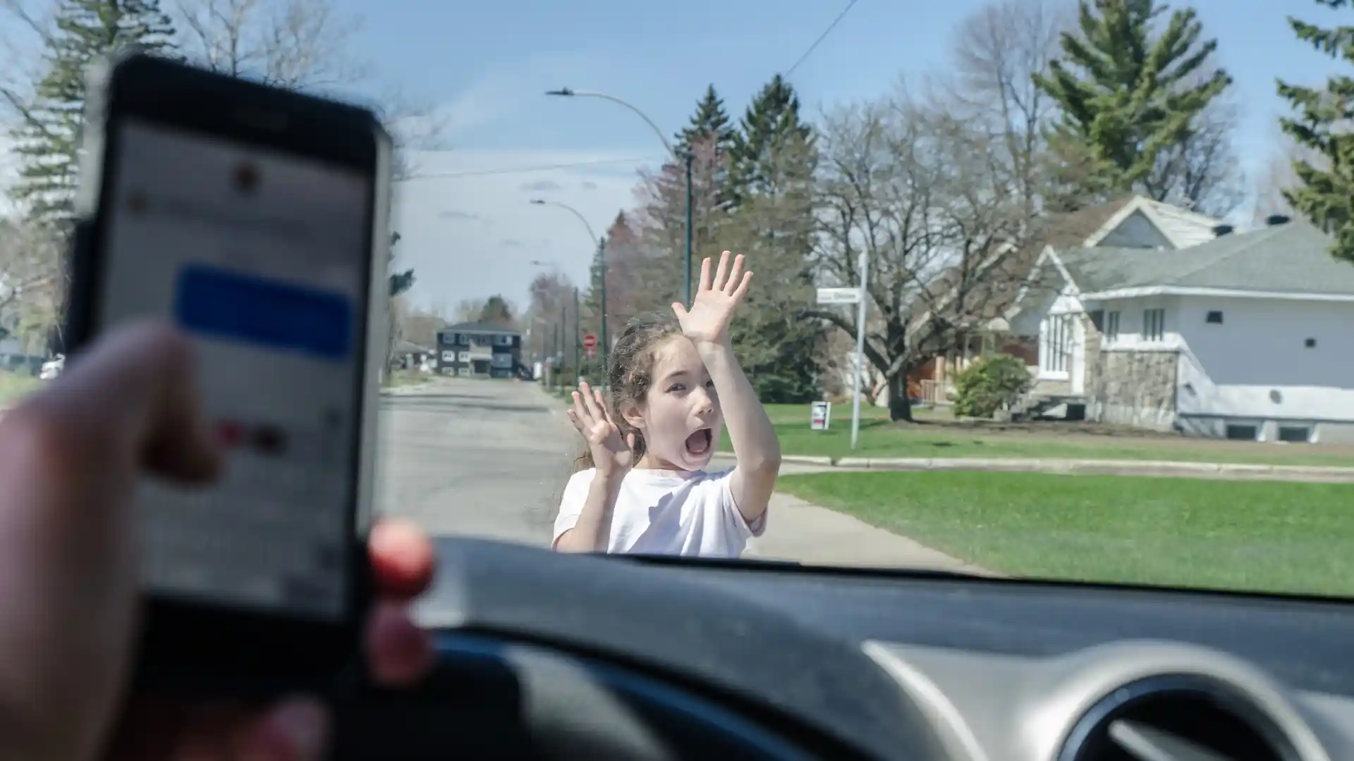 Child in front of car as driver looks at phone