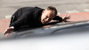 Injured man lying on a car hood after accident